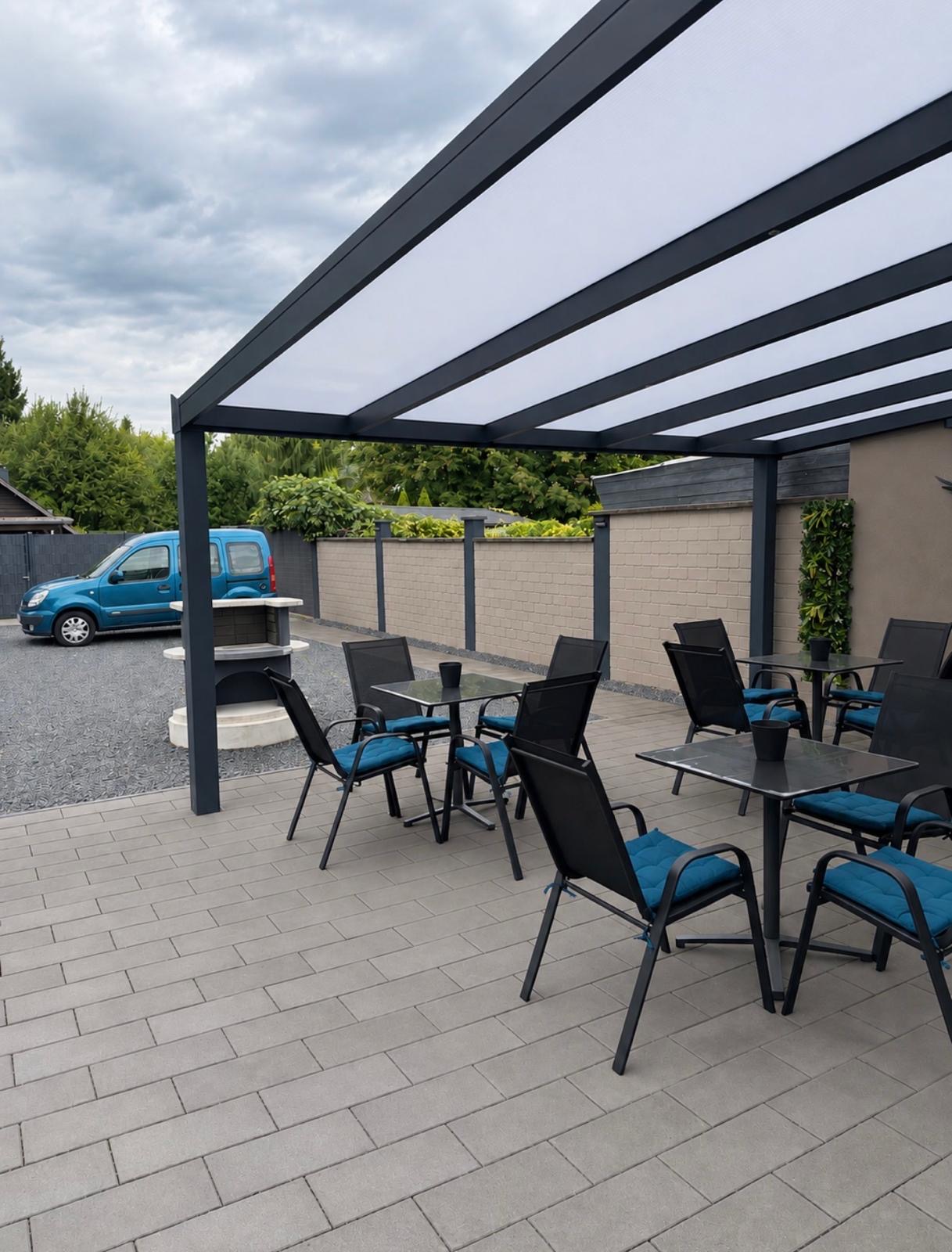 Überdachte Terrasse mit Tischen, Stühlen und Grillplatz
